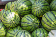 © tai - A bulk pile of fresh, striped watermelons displayed for sale, typical of market produce.