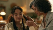 © Fauzi - A mid adult Black woman braids the hair of a mixed race female in a domestic setting, showcasing a traditional hairstyle being made.