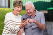 © Austockphoto - mobile phone device held in hand of senior couple as they smile at photos of grandchildren