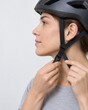 © Daisuke - Adult Adjusting Bicycle Helmet Chin Strap in Studio Close-Up