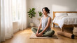 © SecretCanvas - Active woman practicing yoga at home on exercise mat using tree pose for balance strength flexibility and wellness training routine