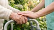 © Wankatsu - Close-up of a young caregiver's hand supporting an elderly woman's hand on a walker in a sunny garden for geriatric healthcare and compassionate elderly care services.