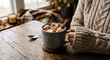 © Kelvin - Mug of hot chocolate with marshmallows and a cinnamon stick on a wooden table with a knit sweater