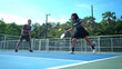 © Wosunan - Male and female pickleball players enjoy playing the game on an outdoor doubles court,
