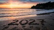 © Zaygun - New year reflection on sandy beach at sunset with the year 2023 written in the sand
