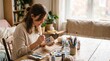 © Thumbs - Woman painting a ceramic mug with blue flowers at a wooden table