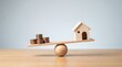 © lolipop - Wooden model house balanced against stacks of coins on a seesaw with real estate property investment housing market financial stability home ownership saving money wealth management mortgage