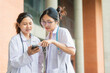 © iPoguz - Asian female medical students looking at smartphone together, young doctors or medical interns using mobile phone at hospital, healthcare workers in lab coats sharing smartphone screen