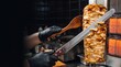 © Ali - Cook slicing chicken shawarma from a vertical spit with a long knife