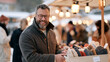 © AnastasiiaRozhmanova - A man with round glasses selling handmade wool hats from a canvas stall in a winter artisan market, rows of colorful knitted goods visible behind him, customers browsing and