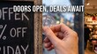 © Mitali Creative  - Person holding a clear suction cup against a glass shop window next to a wooden chalkboard sign with handwritten white chalk text advertising a discount offer