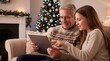 © Vera D - Teenage granddaughter helping her grandfather use a tablet beside a glowing Christmas tree at home, during an authentic shared moment