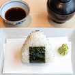 © Pixel-Shot - Japanese cuisine and healthy eating, onigiri rice ball with nori seaweed and wasabi served on a white plate for traditional lunch or snack