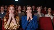 © mihrzn - Two women in a theater react with wide eyes and hands over mouths as they watch an intense performance unfold before them.