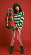 © Miss V - Stylish Christmas elf woman carrying a tall stack of wrapped gifts in bold red, green and white striped clothing, creating a playful festive fashion and holiday shopping concept