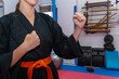 © Manuel - Woman wearing a black dobok and orange belt, practicing hapkido in a dojo, showing a fighting stance