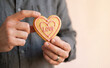 © SimpleDesignStudio - Middle-aged man holding a heart-shaped cookie with the word love for Valentine Day celebration