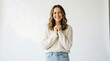 © Alif - Happy young woman holding hands together smiling warmly against a clean white background