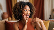 © KAMRAN - Joyful woman with curly hair laughing on orange background spreading happiness and positive energy perfect for upbeat marketing and lifestyle media