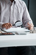 © Charlie's - Close Up Business man Hands Holding Magnifying Glass Over Financial Documents for Audit Fraud Detection and Accounting Investigation