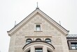 © Timofeeff - Image shows a detailed building facade featuring intricate carvings and geometric patterns, complemented by arched windows and a triangular roof.