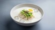© Thilanphuong - bowl of kongguksu (noodles in cold soybean soup).  The thin white wheat noodles are submerged in a thick, creamy, frothy white soy milk broth with a couple of clear ice cubes floating. Garnish consist