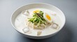 © Thilanphuong - bowl of kongguksu (noodles in cold soybean soup).  The thin white wheat noodles are submerged in a thick, creamy, frothy white soy milk broth with a couple of clear ice cubes floating. Garnish consist
