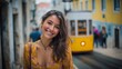 © Envision - Portrait of a cheerful young woman in a floral dress smiling on a narrow city street, with a vintage yellow tram passing behind her, capturing carefree urban lifestyle and travel mood