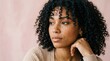 © Coosh448 - Close-up beauty portrait of a Black woman with freckles and dark curls framing her eyes, looking thoughtfully to the side, pale pink studio background, realistic skin texture, soft flattering light,