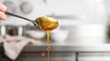 © akridiy - Close-up of a silver spoon dripping golden honey, creating delicious sweet drops in a bright kitchen
