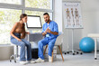 © Pixel-Shot - Chiropractic consultation and spinal health, doctor explaining spine anatomy to patient in medical clinic with skeletal system chart and physical therapy