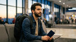 © SUMIDAH - Traveler with a backpack sitting patiently at an airport terminal with a digital device in hand amidst busy surroundings and