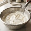 © 행운 행 - 스테인리스 볼에 담긴 크림을 거품기로 젓는 베이킹 반죽 과정 모습Stainless steel bowl with whipping cream and wire whisk for baking preparation
