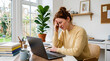 © Babla - Stressed woman sitting at a desk with a laptop and holding her head in generated using ai