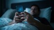 © Zaiseefa - Anonymous guy browsing social media and reading news on a mobile phone while lying in bed.