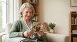 © Alex - Senior woman holding an old black and white photograph in a living room. Elderly female looking at vintage family picture with nostalgia and memories