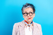 © deagreez - Mature woman portrait with glasses looking puzzled and thoughtful against a bright blue background, stylish short gray hair, scarf and blazer conveying confusion, curiosity and modern fashion