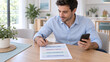 © Mariya Sorvacheva - Father Managing Household Paperwork and Tasks With Smartphone