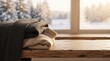© MstRowshanara - Folded wool sweaters on a rustic wooden table against a snowy winter window background