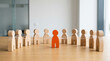 © Dudu - Wooden figurines linked to orange leader by white threads visualize collaborative team structure networking strategy business plan.
