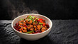 © phumin - A steaming bowl of authentic and flavorful spicy chicken stir-fry, generously garnished with crunchy peanuts and fresh green onions, offering a delightful Asian culinary experience