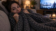 © Yasmin - Young woman relaxing comfortably on a couch wrapped in a cozy blanket.