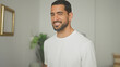 © Krakenimages.com - Man smiling with visible face and beard in a studio apartment interior wearing a white tshirt; friendly confidence.