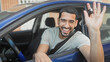 © Krakenimages.com - Young hispanic man in a blue car smiling and waving a key out the open window on a street; joy celebration.
