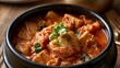 © CRAZY album - Warm, spicy Korean kimchi jjigae with tofu and green onions in a black bowl, isolated on transparent background. Perfect for Asian cuisine ads and menus.