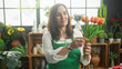 © Krakenimages.com - Woman florist wearing green apron in a building holds and arranges a bouquet of tulips and smiles; gentle care calm.