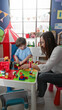 © Krakenimages.com - Woman guiding little boy building colorful toy blocks with hands at play table in building; nurturing calm.