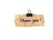 © Eka - Handwritten thank you note on torn brown craft paper held by a black binder clip isolated on white. Perfect design element for appreciation concepts, business gratitude, and greeting card templates