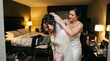 © woters - A woman helps the beautiful bride put on a white veil in her room.