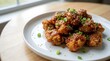 © FrameBloom Studio - Delicious asian style chicken bites with sesame seeds and green onions on a round plate. general tso